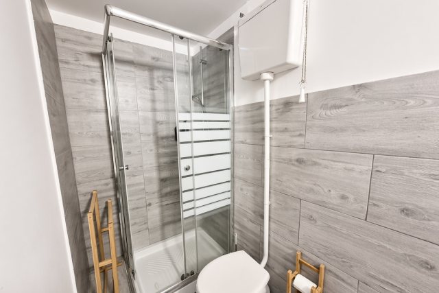 Doccia con box in cristallo e piatto doccia, accanto al wc